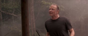 Movie still from “Anaconda” (1997), directed by Luis Llosa – A man in a black t - shirt is holding a pole; Close Up shot, Low angle