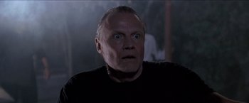 Movie still from “Anaconda” (1997), directed by Luis Llosa – An older man with a goatee stares at the camera; Close Up shot, Low angle