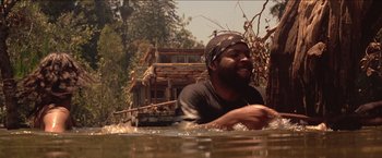 Movie still from “Anaconda” (1997), directed by Luis Llosa – A man in a black shirt is swimming in a body of water; Medium shot, Low angle
