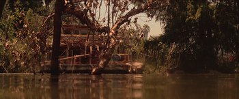 Movie still from “Anaconda” (1997), directed by Luis Llosa – A boat is traveling down a river next to a tree; Extreme Wide shot, Low angle