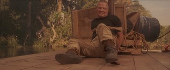 Movie still from “Anaconda” (1997), directed by Luis Llosa – A man sitting on the ground tied to a wooden crate; Wide shot, Low angle