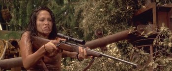 Movie still from “Anaconda” (1997), directed by Luis Llosa – A woman holding a rifle and aiming it with a rifle scope; Medium shot, Low angle