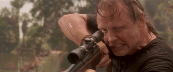 Movie still from “Anaconda” (1997), directed by Luis Llosa – A man is holding a rifle and aiming at something; Close Up shot, Over the shoulder angle