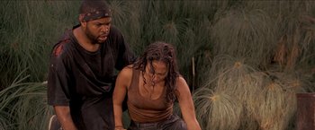 Movie still from “Anaconda” (1997), directed by Luis Llosa – A man and a woman are in the grass; Medium shot, High angle