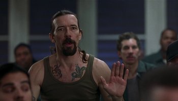 Movie still from “Analyze That” (2002), directed by Harold Ramis – A man with long hair and a tattoo on his chest; Close Up shot, Over the shoulder angle