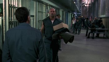 Movie still from “Analyze That” (2002), directed by Harold Ramis – A man walking down the street holding a box; Medium shot, Over the shoulder angle