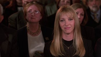 Movie still from “Analyze That” (2002), directed by Harold Ramis – A woman standing in front of a crowd of people; Close Up shot, Over the shoulder angle