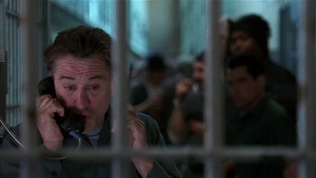 Movie still from “Analyze That” (2002), directed by Harold Ramis – A group of people standing in front of a cage; Medium shot, Low angle