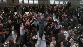 Movie still from “Analyze That” (2002), directed by Harold Ramis – A group of people sitting in a room with a man on a stage; Wide shot, Overhead angle