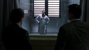 Movie still from “Analyze That” (2002), directed by Harold Ramis – A man standing in front of a mirror in a jail cell; Wide shot, Over the shoulder angle
