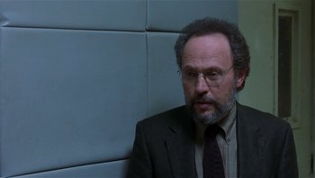 Movie still from “Analyze That” (2002), directed by Harold Ramis – A man in a suit and tie sitting in front of a wall; Close Up shot, Over the shoulder angle