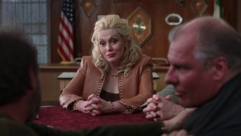 Movie still from “Analyze That” (2002), directed by Harold Ramis – A woman sitting at a table in front of a judge; Medium shot, Over the shoulder angle