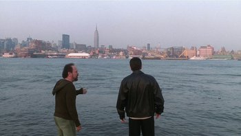 Movie still from “Analyze That” (2002), directed by Harold Ramis – Two men standing on the edge of a body of water; Extreme Wide shot, High angle
