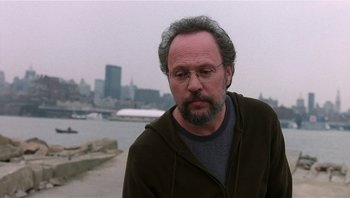 Movie still from “Analyze That” (2002), directed by Harold Ramis – A man with a beard and glasses is standing by the water; Close Up shot, Over the shoulder angle