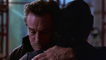 Movie still from “Analyze That” (2002), directed by Harold Ramis – A person hugging another person; Close Up shot, Over the shoulder angle
