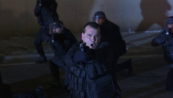 Movie still from “Analyze That” (2002), directed by Harold Ramis – A group of men in black uniforms holding guns; Medium shot, Low angle