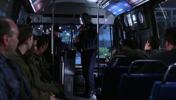 Movie still from “Analyze That” (2002), directed by Harold Ramis – A man standing on a public transit bus; Wide shot, Over the shoulder angle