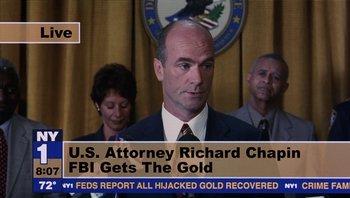 Movie still from “Analyze That” (2002), directed by Harold Ramis – A man in a suit and tie in front of a podium; Extreme Close Up shot, Low angle