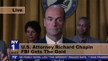 Movie still from “Analyze That” (2002), directed by Harold Ramis – A man in a suit and tie in front of a picture of a building; Extreme Close Up shot, Low angle