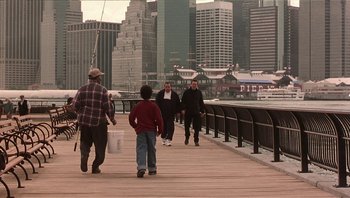 Movie still from “Analyze That” (2002), directed by Harold Ramis – A group of people walking on a pier near a body of water; Wide shot, High angle