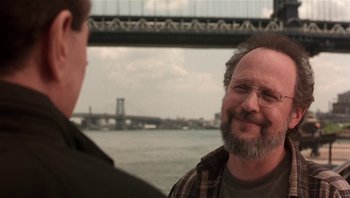 Movie still from “Analyze That” (2002), directed by Harold Ramis – A man with a beard is talking to another man in front of a bridge; Close Up shot, Over the shoulder angle