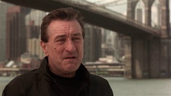 Movie still from “Analyze That” (2002), directed by Harold Ramis – A person wearing a jacket near a bridge; Close Up shot, Low angle