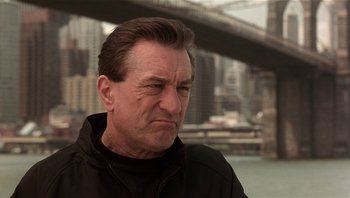 Movie still from “Analyze That” (2002), directed by Harold Ramis – A person wearing a jacket near a body of water; Close Up shot, Low angle