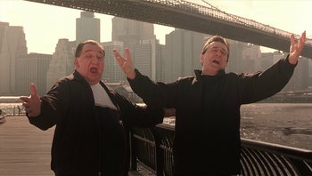 Movie still from “Analyze That” (2002), directed by Harold Ramis – A couple of men standing next to each other on top of a bridge; Medium shot, Low angle