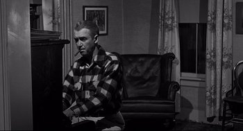 Movie still from “Anatomy of a Murder” (1959), directed by Otto Preminger – A black and white photo of a man sitting in a living room; Medium shot, High angle