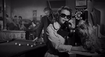 Movie still from “Anatomy of a Murder” (1959), directed by Otto Preminger – A woman talking on a phone while standing next to a pool table; Medium shot, Low angle