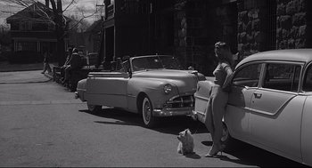 Movie still from “Anatomy of a Murder” (1959), directed by Otto Preminger – A woman standing on the side of the road next to a car; Wide shot, Low angle