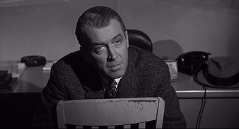 Movie still from “Anatomy of a Murder” (1959), directed by Otto Preminger – A man in a suit sitting at a desk; Close Up shot, Over the shoulder angle