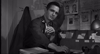 Movie still from “Anatomy of a Murder” (1959), directed by Otto Preminger – A black and white photo of a man sitting at a desk; Medium shot, Low angle