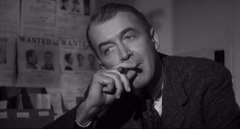 Movie still from “Anatomy of a Murder” (1959), directed by Otto Preminger – An older man is smoking a cigarette while wearing a suit and tie; Close Up shot, Low angle