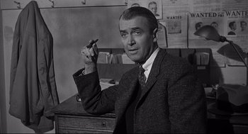 Movie still from “Anatomy of a Murder” (1959), directed by Otto Preminger – A man in a suit and tie holding a pen; Medium shot, Low angle