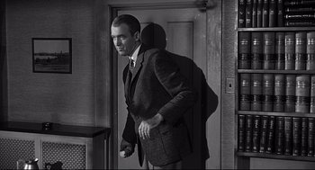 Movie still from “Anatomy of a Murder” (1959), directed by Otto Preminger – A black and white photo of a man standing in front of an open door; Medium shot, Low angle