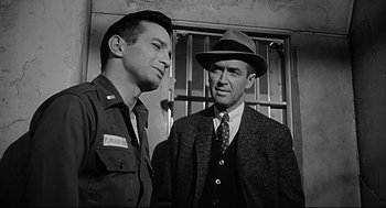 Movie still from “Anatomy of a Murder” (1959), directed by Otto Preminger – Two men standing next to each other in front of bars; Close Up shot, Over the shoulder angle