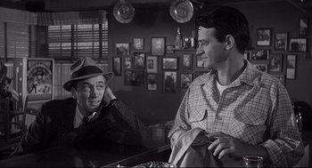 Movie still from “Anatomy of a Murder” (1959), directed by Otto Preminger – Two men are talking in a room with pictures on the wall; Medium shot, Over the shoulder angle