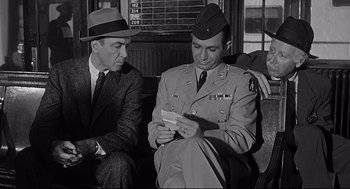 Movie still from “Anatomy of a Murder” (1959), directed by Otto Preminger – Two men in suits and hats are looking at a piece of paper; Medium shot, Over the shoulder angle