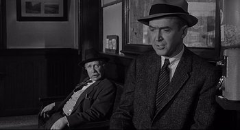 Movie still from “Anatomy of a Murder” (1959), directed by Otto Preminger – A man in a suit and a man in a hat; Medium shot, Over the shoulder angle