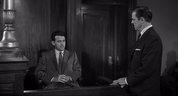 Movie still from “Anatomy of a Murder” (1959), directed by Otto Preminger – Two men in suits are sitting at a table; Medium shot, Over the shoulder angle