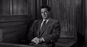 Movie still from “Anatomy of a Murder” (1959), directed by Otto Preminger – Black and white photograph of a man in a suit and tie; Medium shot, Low angle