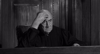 Movie still from “Anatomy of a Murder” (1959), directed by Otto Preminger – An older man in a courtroom with his hand on his head; Close Up shot, High angle