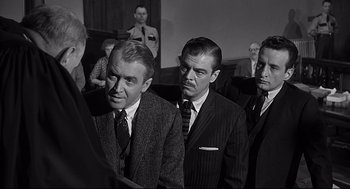Movie still from “Anatomy of a Murder” (1959), directed by Otto Preminger – Black and white photograph of men in suits and ties; Medium shot, Over the shoulder angle