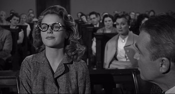 Movie still from “Anatomy of a Murder” (1959), directed by Otto Preminger – A woman with glasses in front of a group of people; Medium shot, Over the shoulder angle