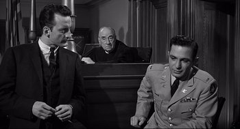 Movie still from “Anatomy of a Murder” (1959), directed by Otto Preminger – Three men in suits sitting in front of each other in a courtroom; Medium shot, Over the shoulder angle