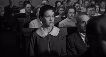 Movie still from “Anatomy of a Murder” (1959), directed by Otto Preminger – An old photo of a woman in a crowd of people; Medium shot, Low angle
