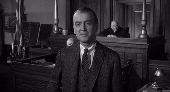 Movie still from “Anatomy of a Murder” (1959), directed by Otto Preminger – A man wearing a suit and tie in a courtroom; Medium shot, Low angle