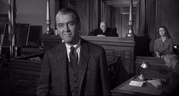 Movie still from “Anatomy of a Murder” (1959), directed by Otto Preminger – A black and white photo of a man in a courtroom; Medium shot, Low angle