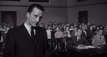 Movie still from “Anatomy of a Murder” (1959), directed by Otto Preminger – A man standing in front of a group of people in a courtroom; Medium shot, Low angle